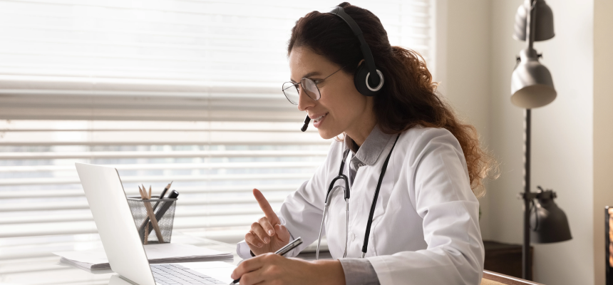 A nurse checking records on a tablet at a busy nurses station