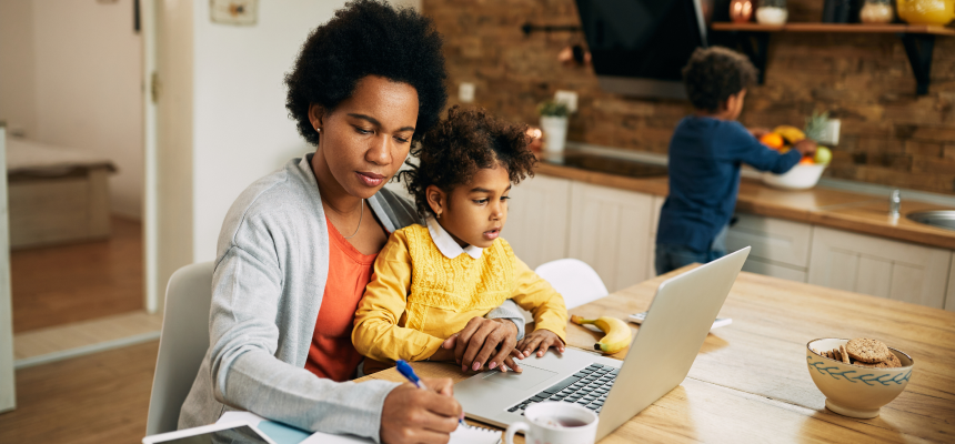 Online learner working on the computer with a child on her lap